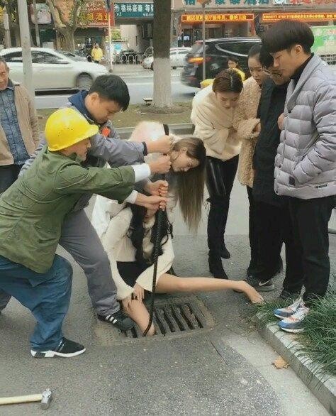 郑州一美女走路玩手机 脚卡进了臭水沟里