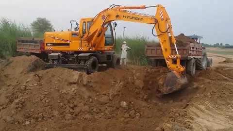 巴基斯坦工地,工人驾驶现代挖掘机给拖拉机装土