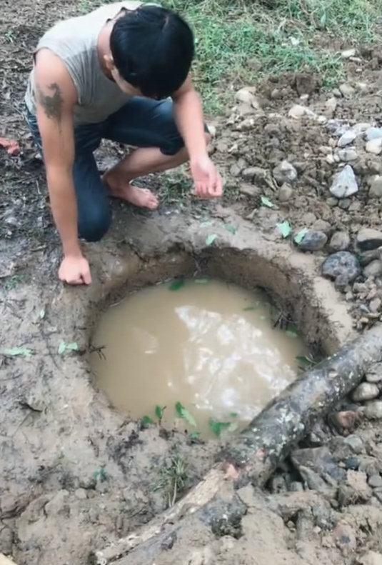 积满水的地洞浑黄无比小伙头上脚下钻进去还真抓起鱼来