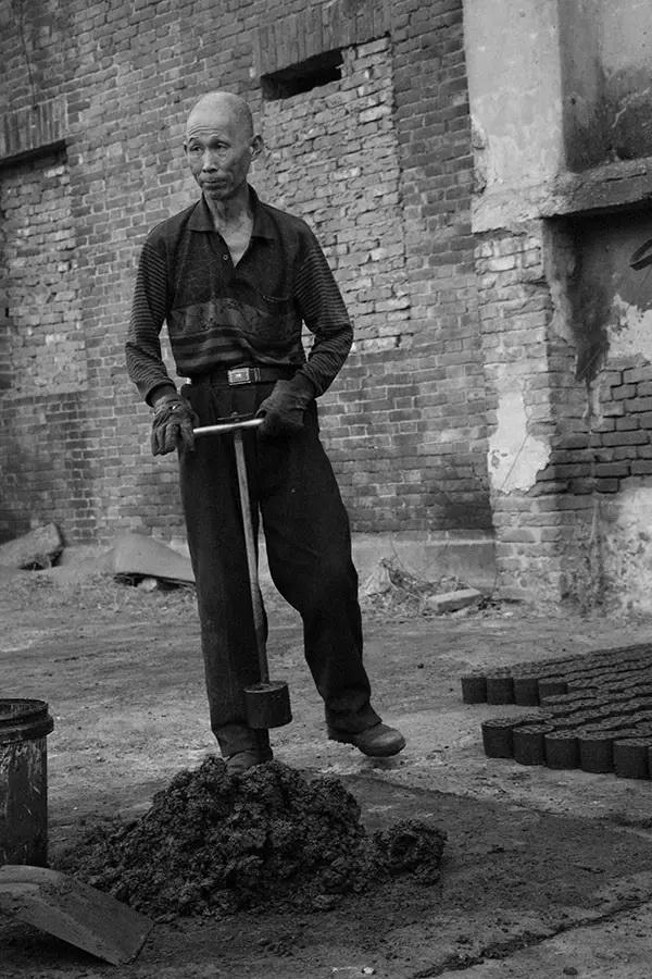 区沿江东路棚户区,一家做煤球生意的加工厂门口这位老人正在打煤球