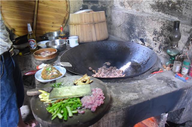 实拍农村人准备午餐土灶上一口大铁锅一边炒菜边劈柴