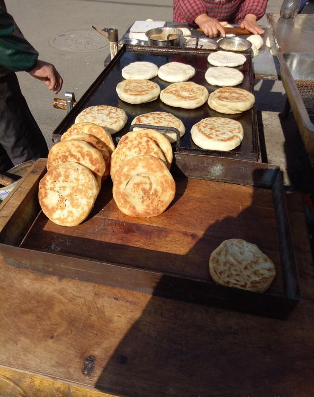 夫妻俩在街头卖烧饼,做的没有卖的快,一个个称重后再卖