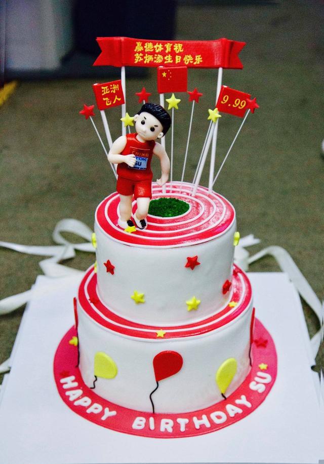 蛋糕图案为红色跑道,绿色草坪,上面的小人代表苏炳添,后面的9秒99是