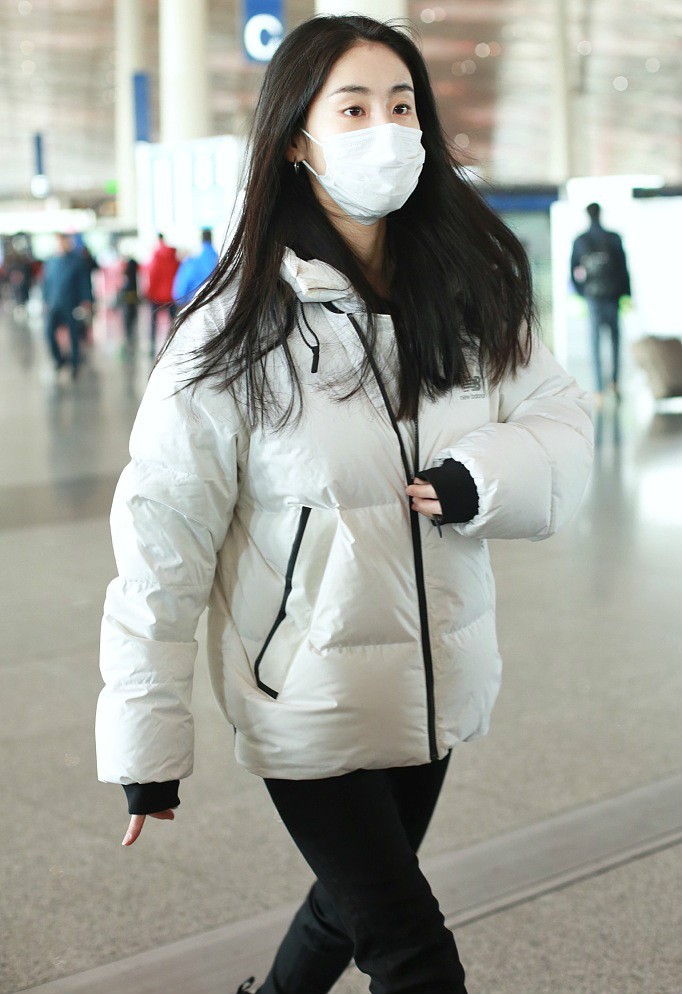张碧晨身着白色羽绒服口罩遮面现身机场 大步流星气场十足