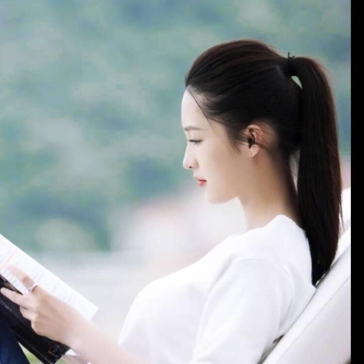 这一张,李沁扎着一个干净利落的马尾,躺在户外沙发上看书,一身白色