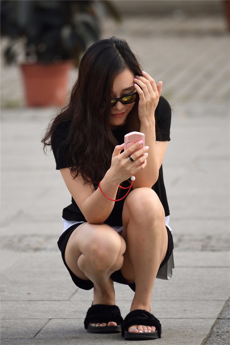 路人街拍,在人来人往的马路上蹲着玩手机的美女,脚指甲也是亮点