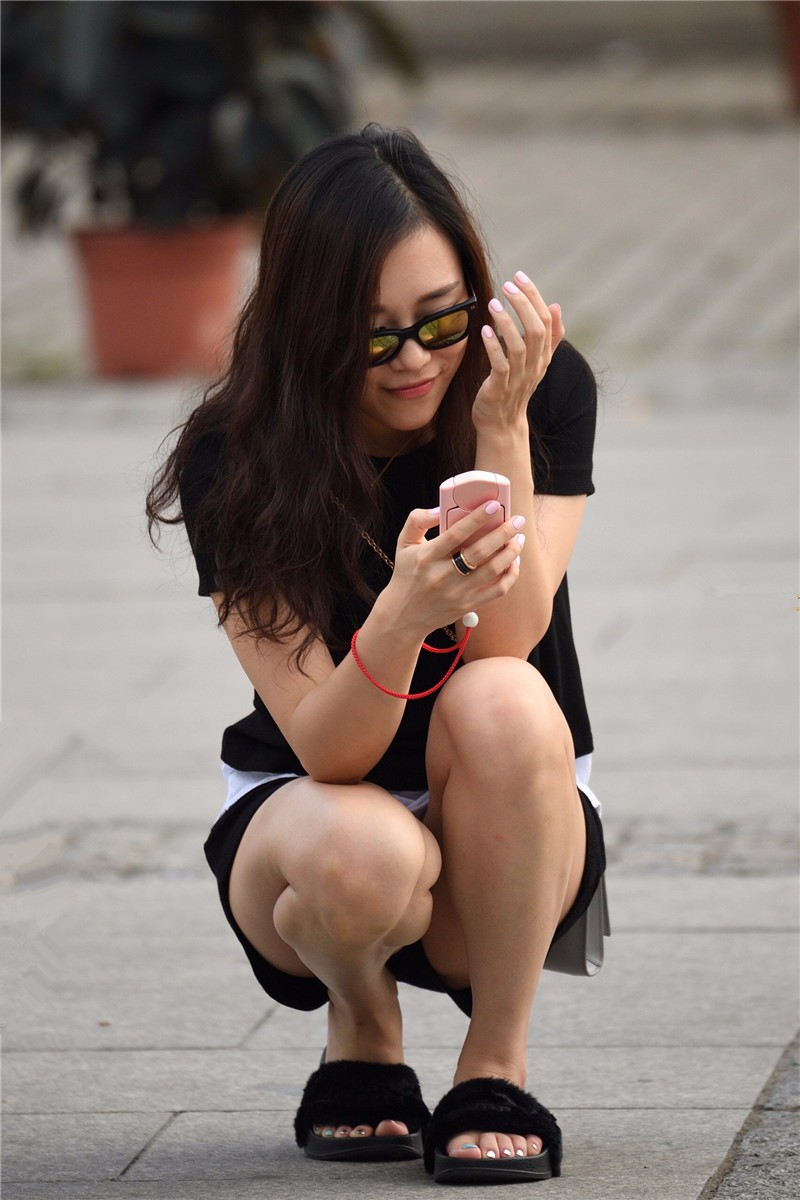 路人街拍,在人来人往的马路上蹲着玩手机的美女,脚指甲也是亮点