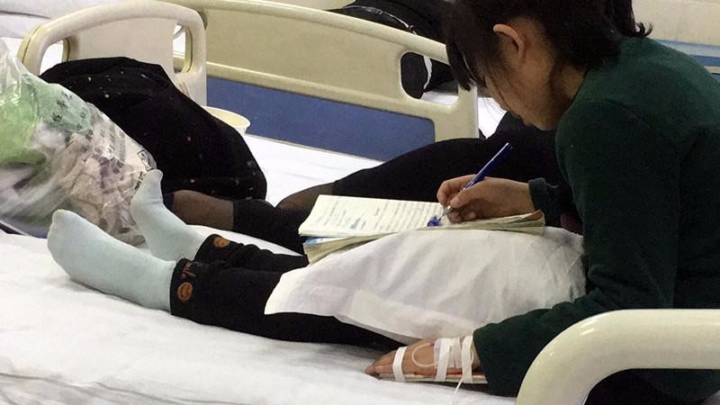 作业繁多 小学生边输液边写作业