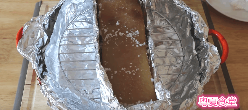 把烤好的五花肉取出来后,把上面的粗盐和锡纸去掉,再用尖竹签在猪皮