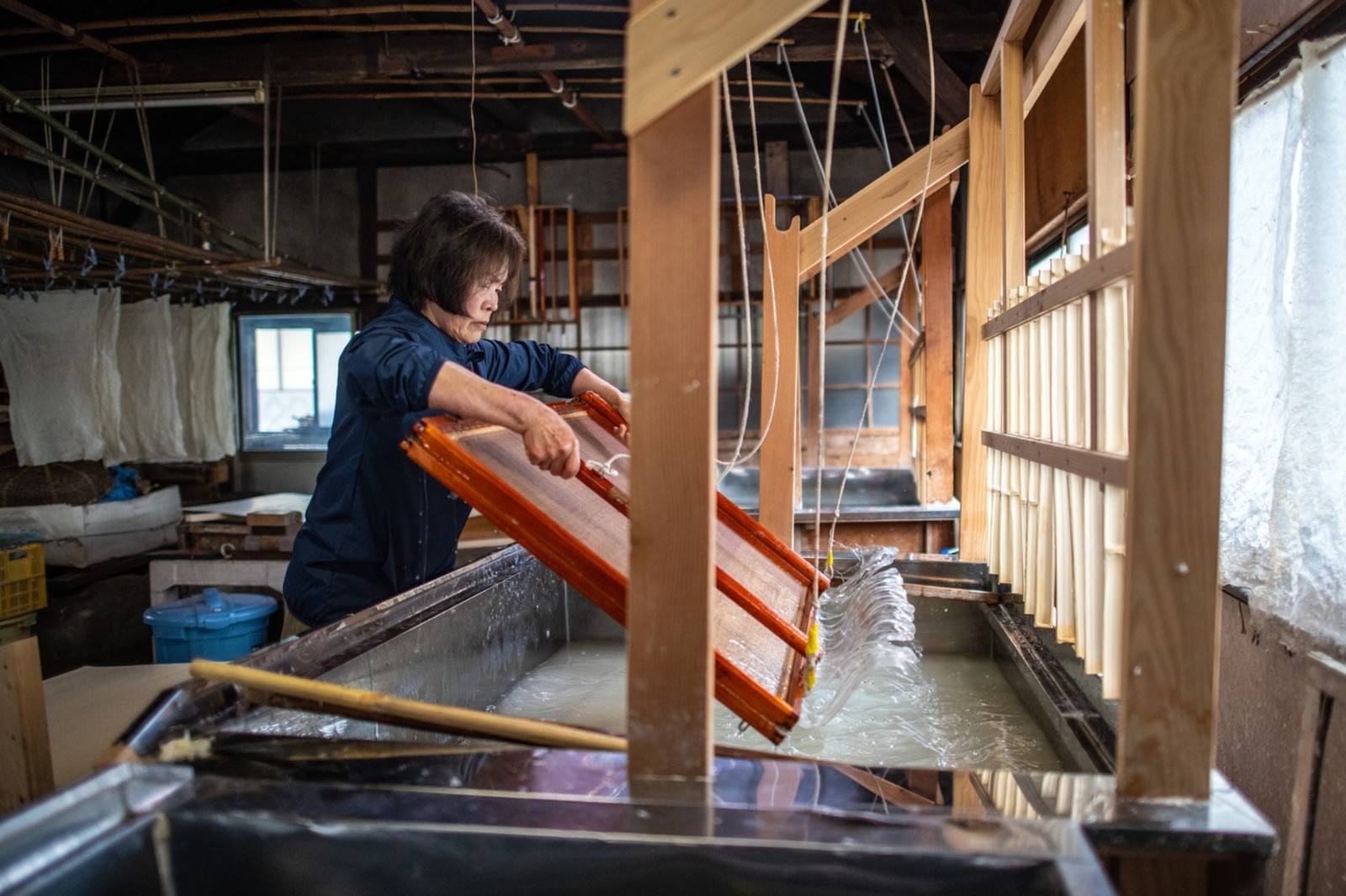 图为内村久子晃动竹筛,使纸浆的纤维平均散布筛网上面.