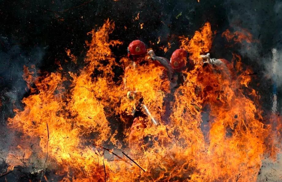只见多名全副武装的"橙色勇士"背负着灭火机具向熊熊燃烧的大火发起