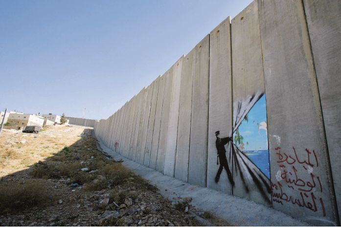 2005年8月6日,约旦河西岸拉马拉,英国涂鸦艺术家班克西在巴以隔离墙上