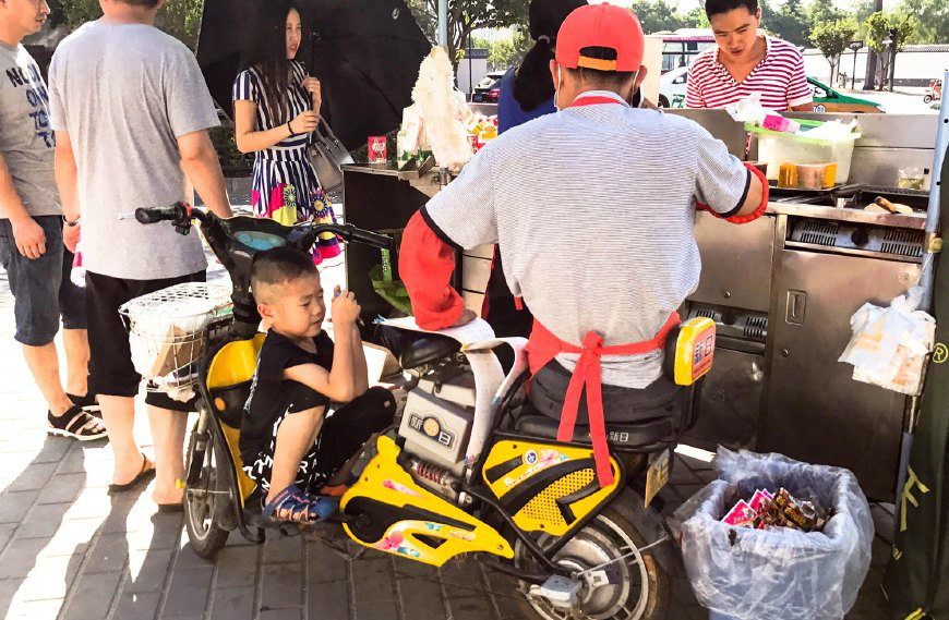 5岁童跟父母出摊儿电动车座椅成他的课桌