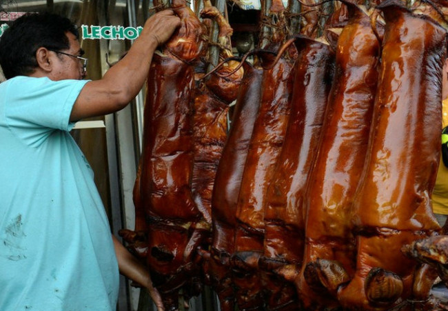 图为工人将刚烤好的乳猪挂好.