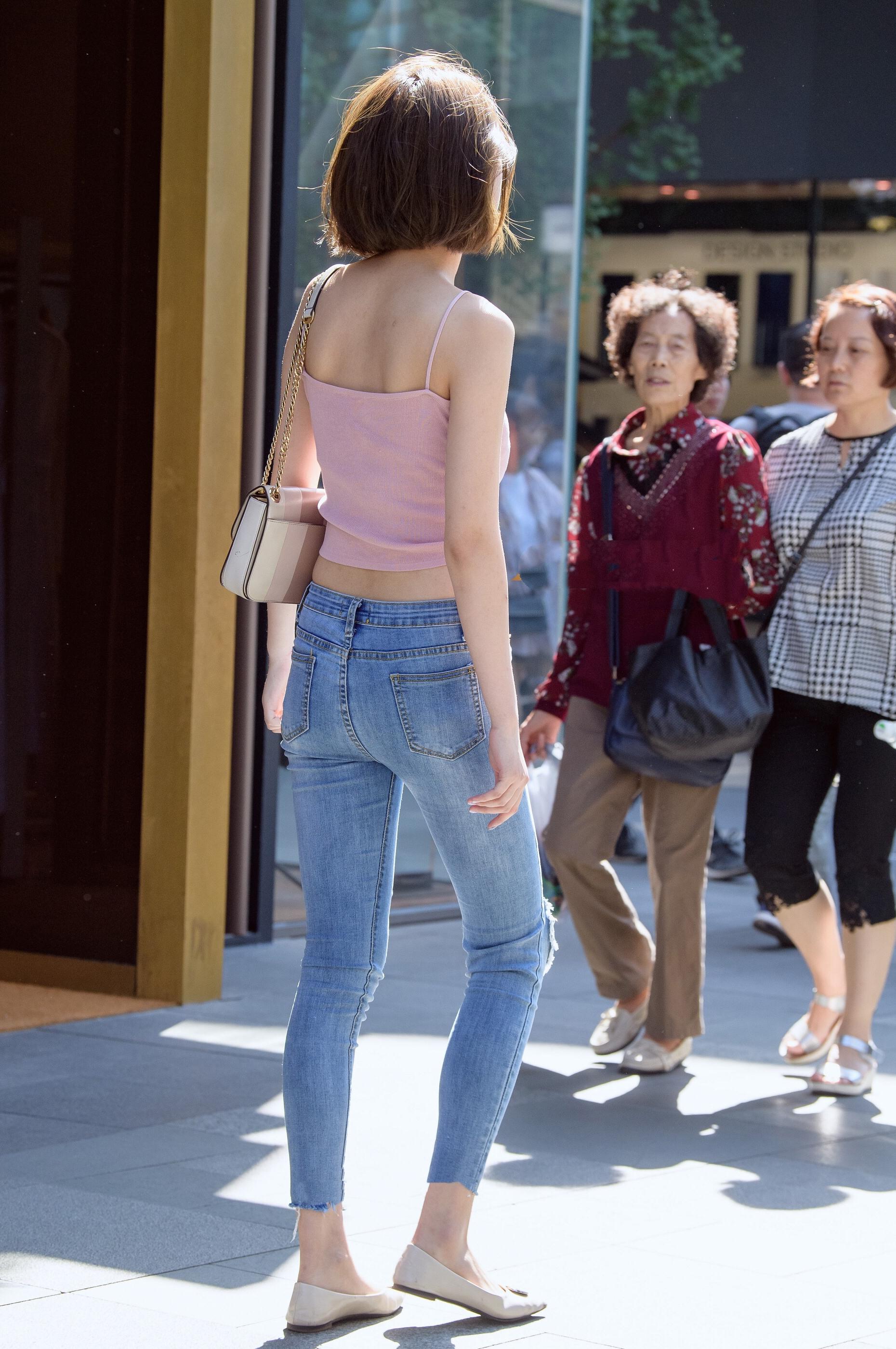 紧身牛仔裤配粉色吊带上衣,小姐姐身材凹凸有致,打扮迷人