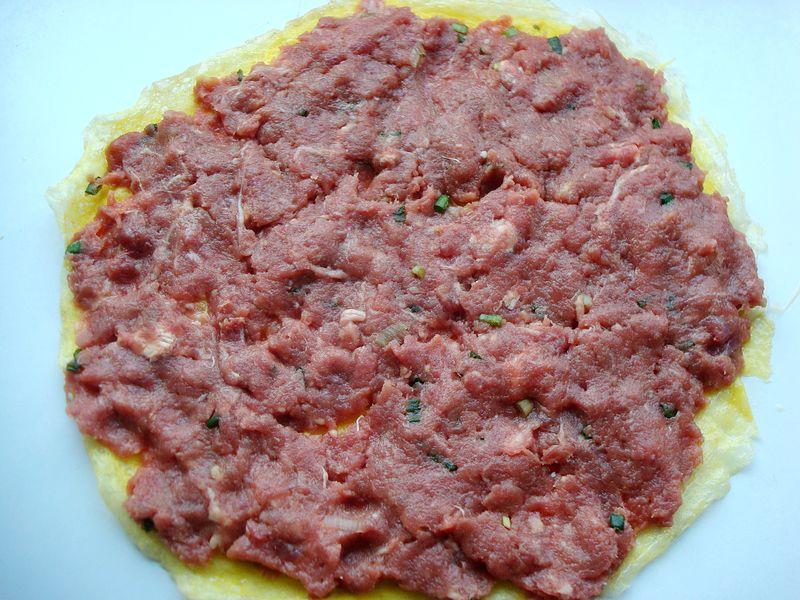 8,把一边蛋皮卷起来,一直卷完为止,用手轻轻拍打肉馅,排出肉馅中的