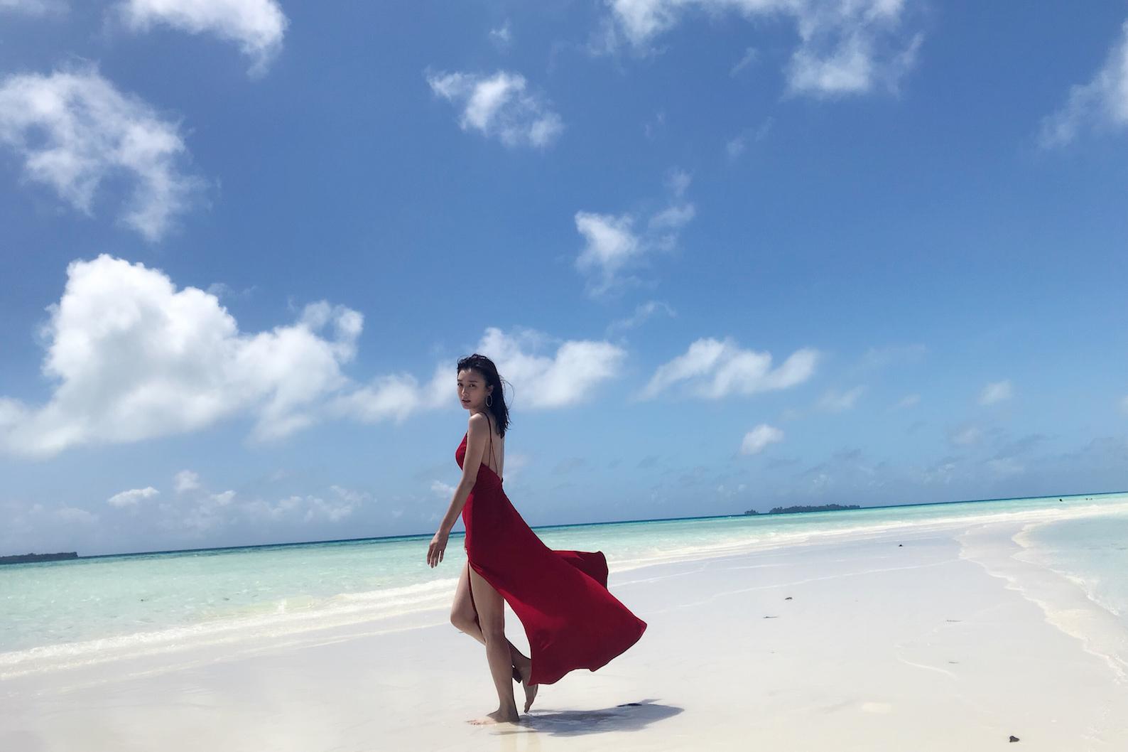 红色吊带长裙,裸背香肩尽显风情,海天一色,光脚漫步在沙滩上慵懒随性