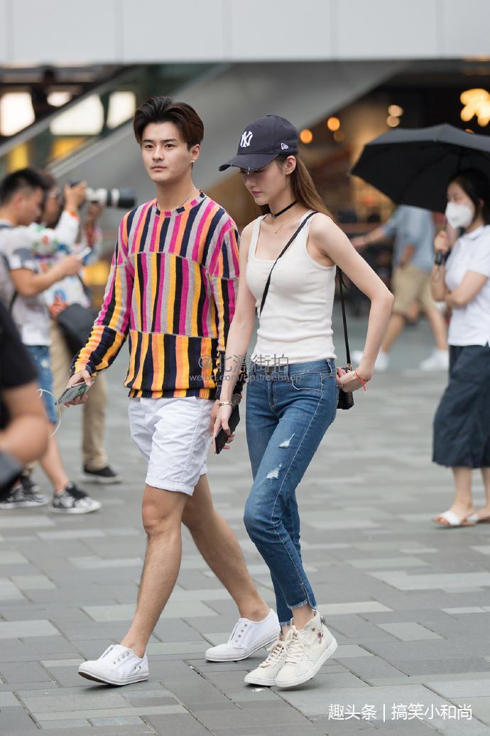 路人街拍小姐姐牛仔短裤搭配红色针织短衫一双小白鞋步履轻盈