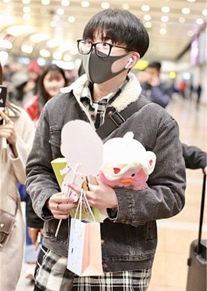 费启鸣现身机场,戴口罩和眼镜低调现身,抱粉丝所送公仔显萌态