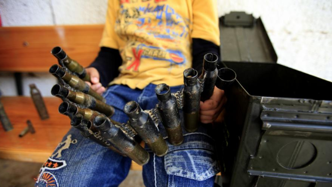 一个流离失所的孩子正在玩耍他的玩具-空弹壳.