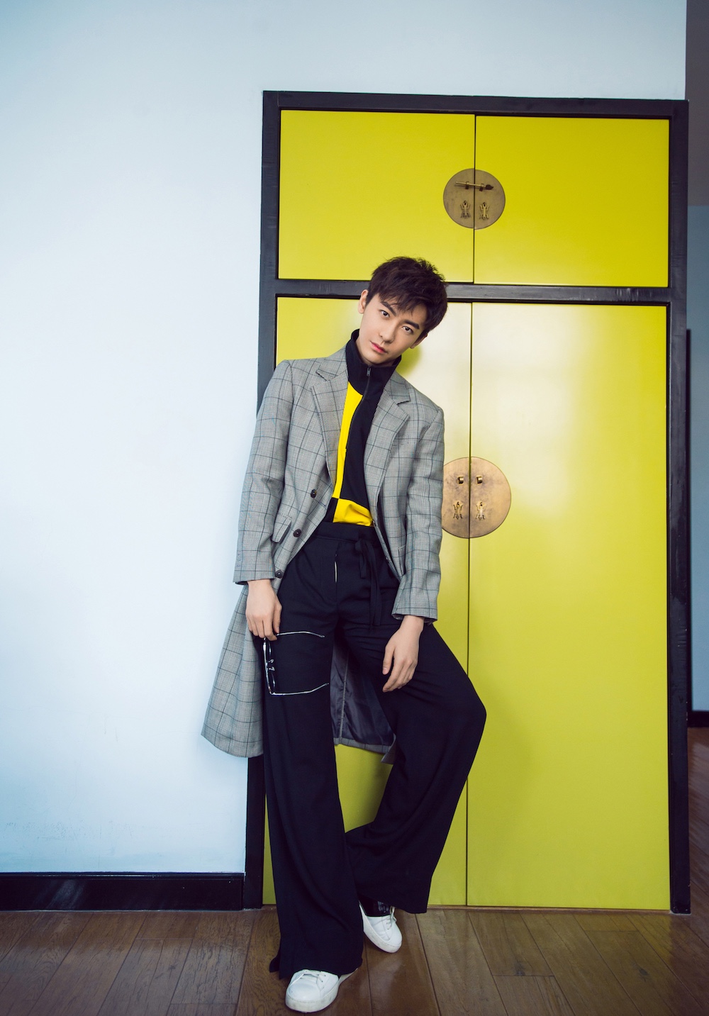 镜头中的赵志伟高领短袖衬衣搭配高腰阔腿裤,倚墙而立时尽显优越身材