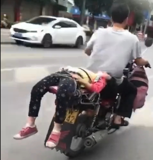 女儿哭闹表示不愿意上学,父亲却将其绑摩托车后座送上学!