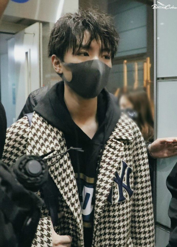 王俊凯戴黑色口罩穿风衣现身机场头发好像没有梳看起来有点凌乱