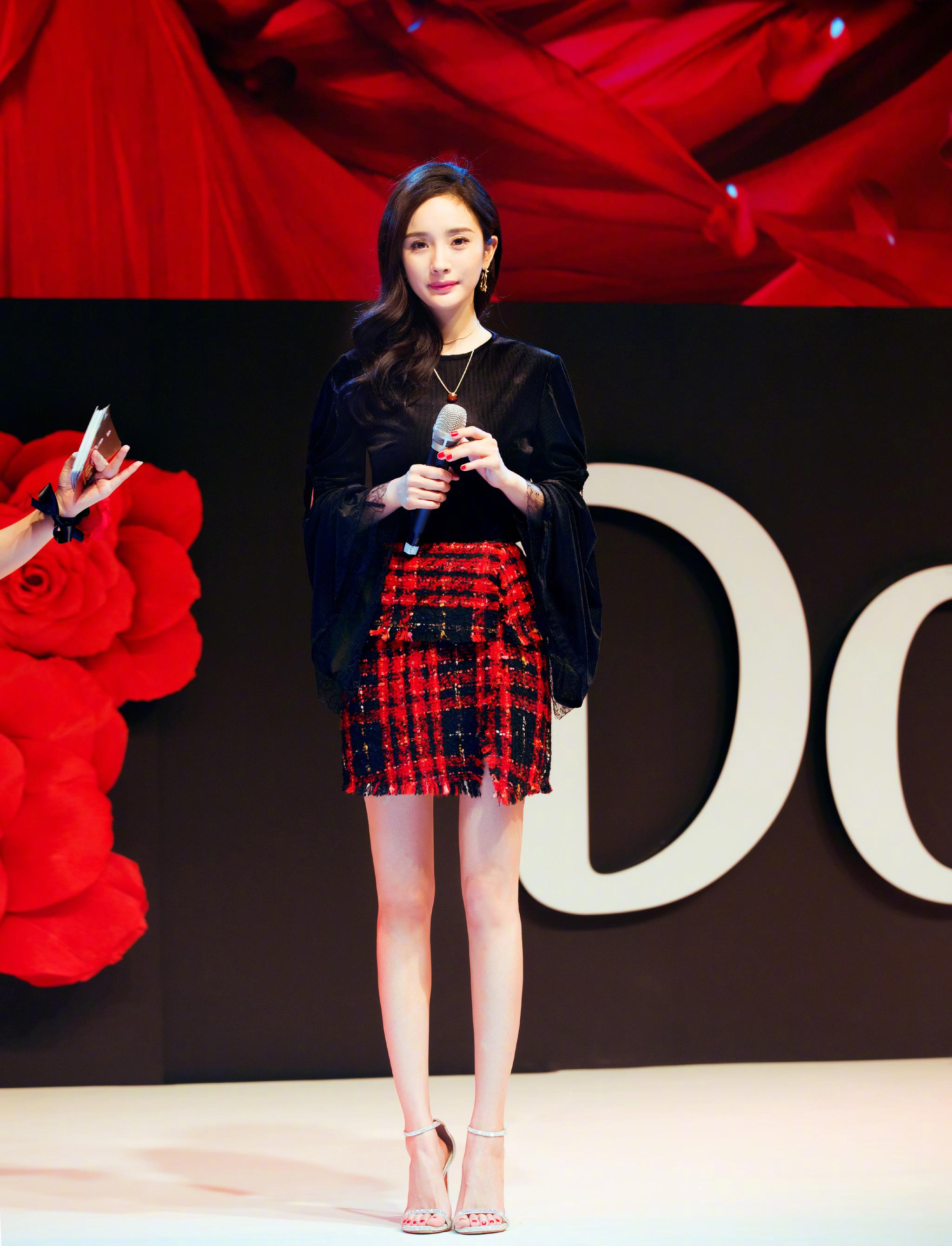 杨幂身穿一件黑色上衣,下身搭配一件给子短裙.