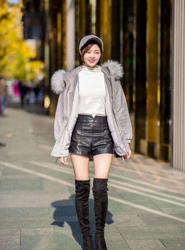 白色上衣搭配黑色皮短裤,过膝长靴,一位非常时尚的小姐姐