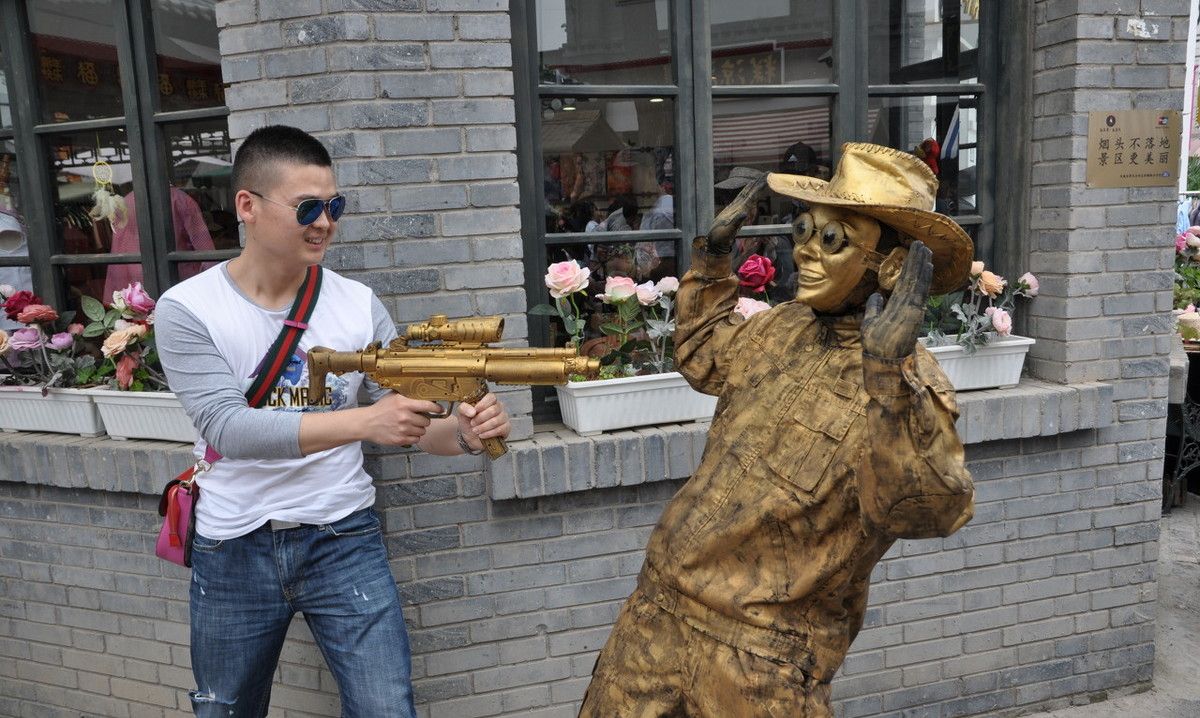 一个头戴西部牛仔帽,手拿玩具枪的"铜人",在景区"站桩"表演