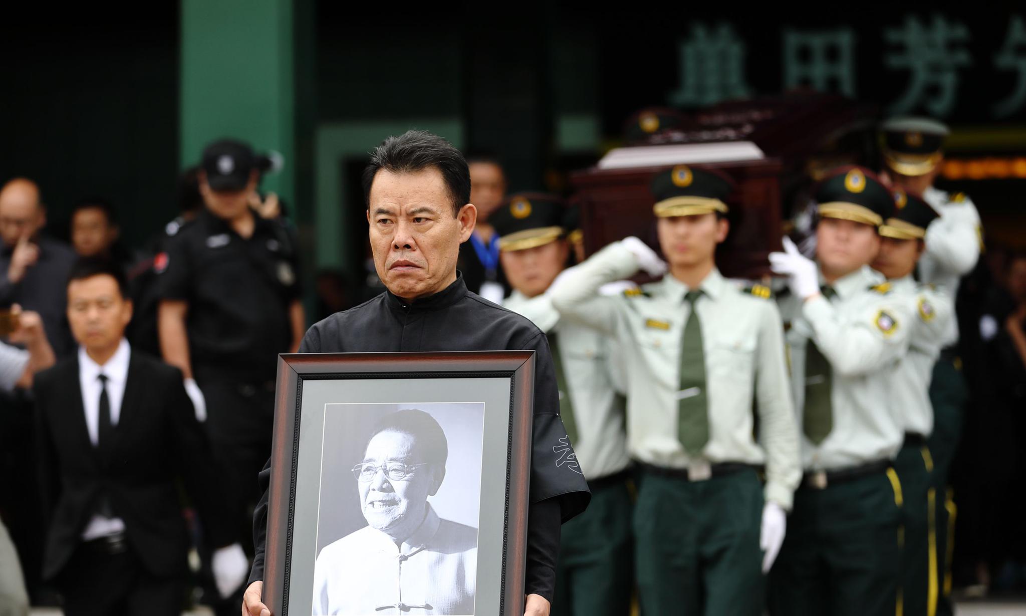 表演艺术家单田芳的告别仪式举行,单田芳之子单瑞林手捧父亲遗像送别