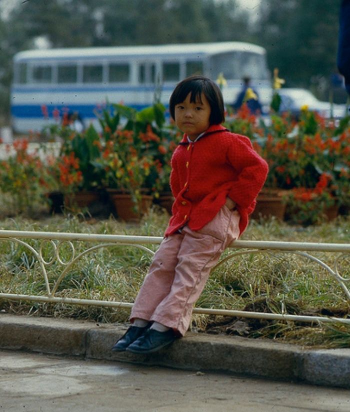图为八十年代沈阳街头的一位小姑娘,红色外套粉色裤子,一个人坐在路边