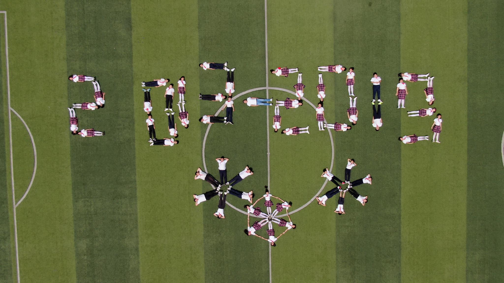 小学操场上,近百小学毕业生在操场上摆出各种各样的创意毕业照造型