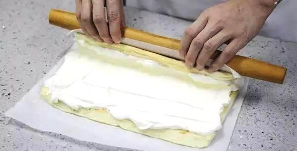 15,用擀面杖顶着蛋糕往前卷,同时油纸慢慢往后卷.