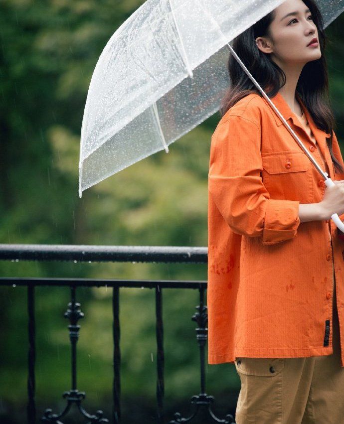 李沁橘色工装外套,雨中漫步显文艺,手持透明伞上演唯美侧颜杀_高清