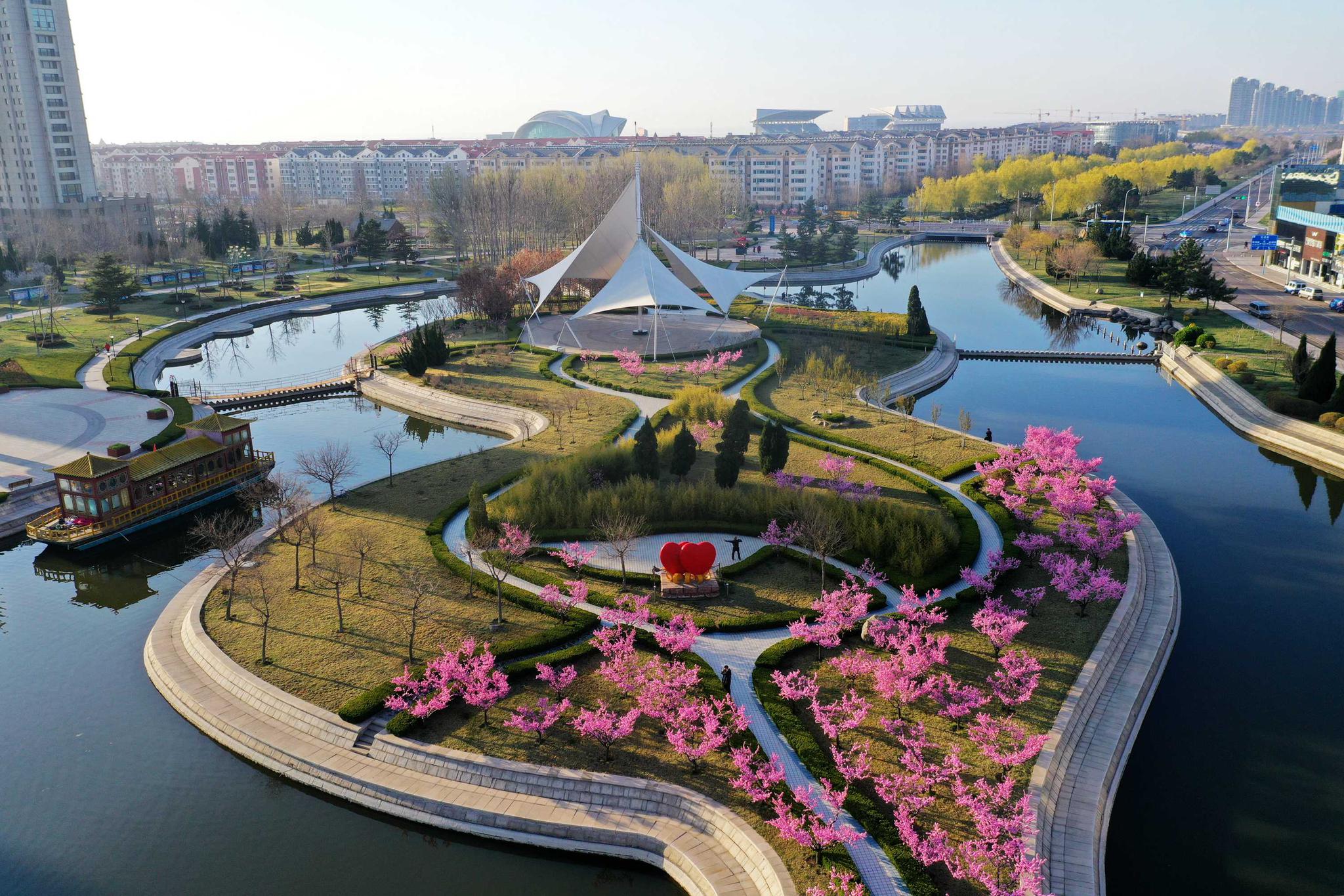 在毗邻海边的荣成市滨海公园,蔚蓝的大海,散落的木船与公园里吐