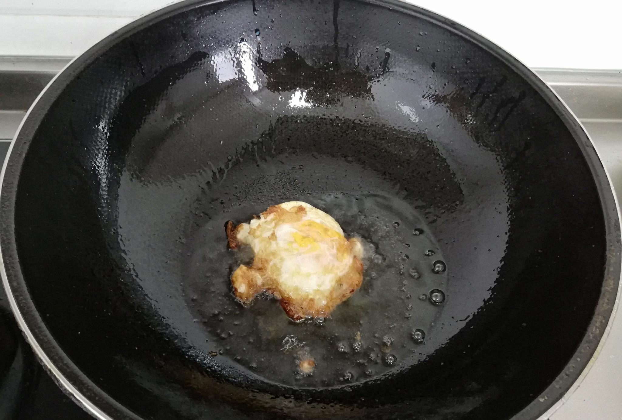 热锅上油,打入一个鸡蛋,进行煎制,油里面提前可以放入一些食盐,中火煎