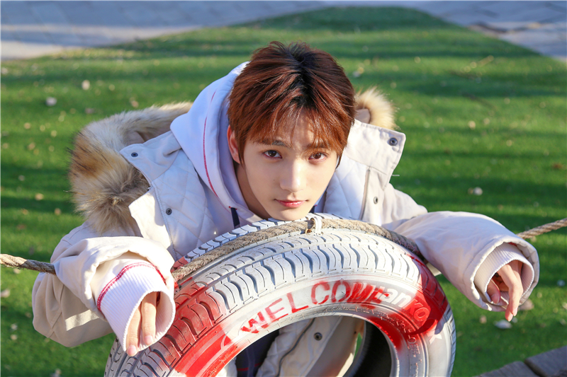 照片中,祁宋身穿米白色短款羽绒服,搭配黑白红三色