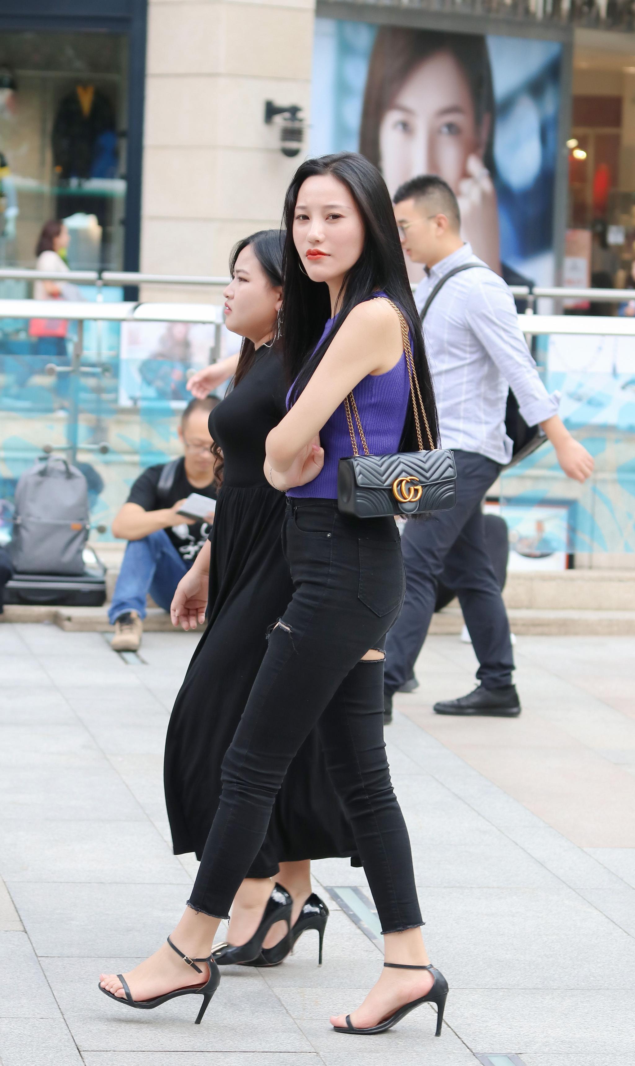 街拍美女双手环抱胸前露肩背心配紧身牛仔裤尽显紧致好身材