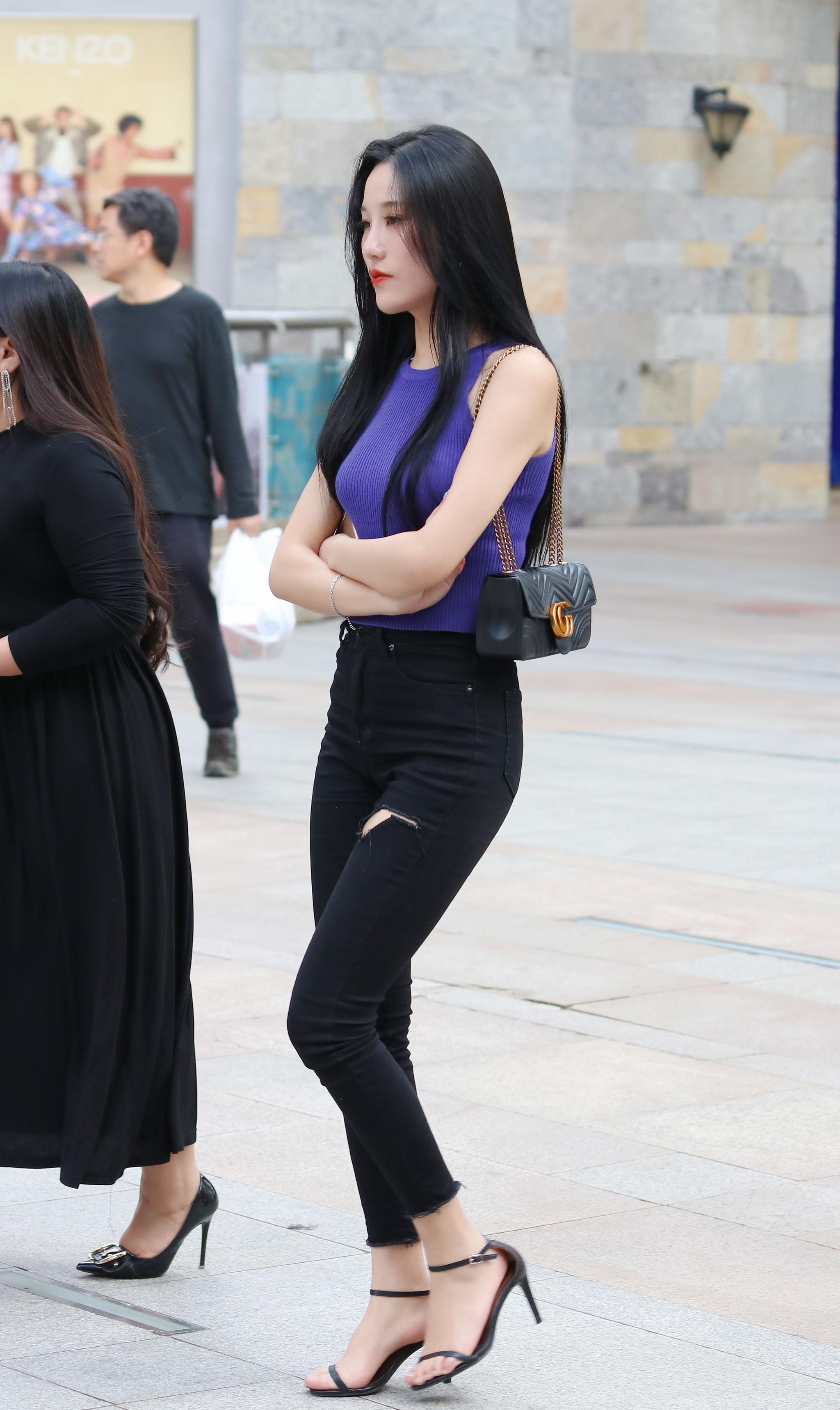 街拍美女双手环抱胸前露肩背心配紧身牛仔裤尽显紧致好身材