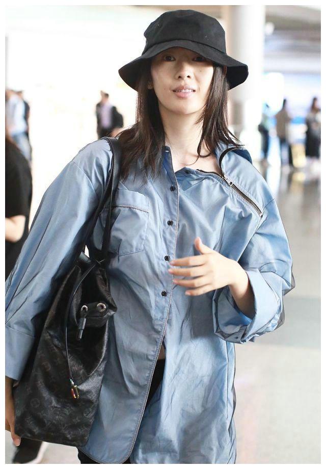 女演员童瑶素颜现身,穿蓝色衬衫黑色紧身裤,戴渔夫帽呆萌可爱