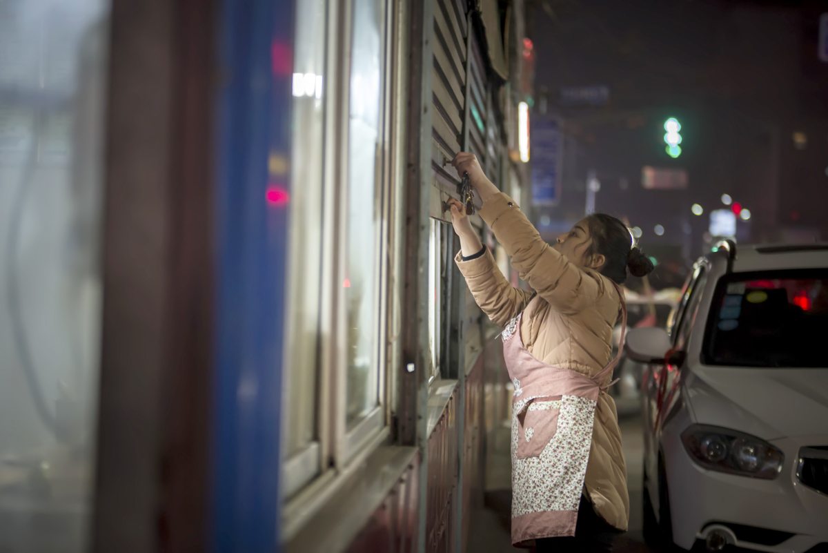 已是深夜时分,看到再没有客人来吃饭,黄楠杰帮爸爸拉下简易房的卷闸门