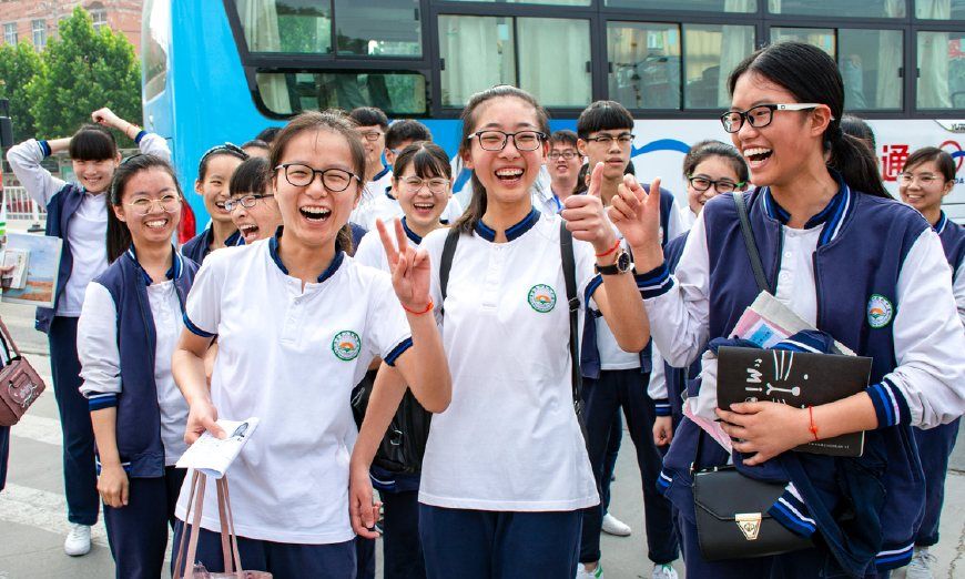 滑县六中考点大门前,刚下车准备考试的3名女考生做出胜利的手势.