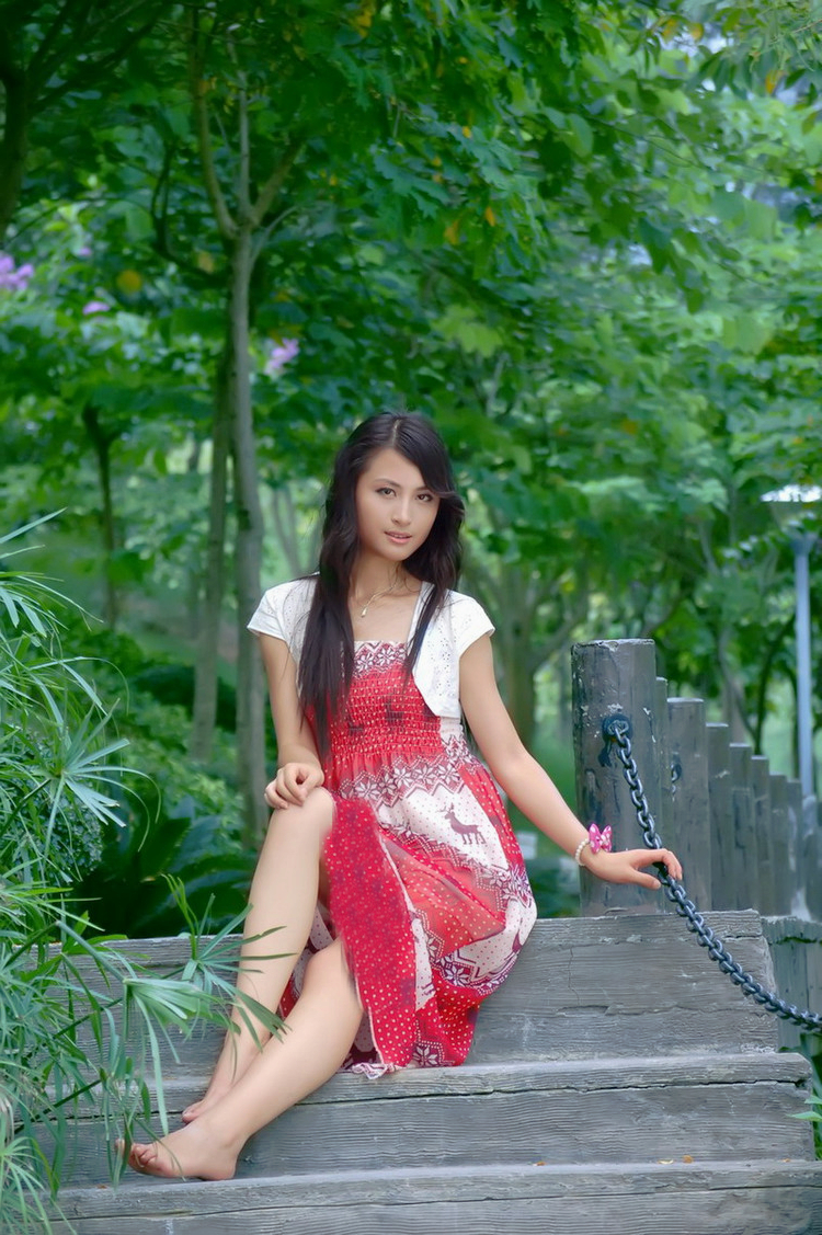 一个依偎在公园美景下的秀丽美裙女子