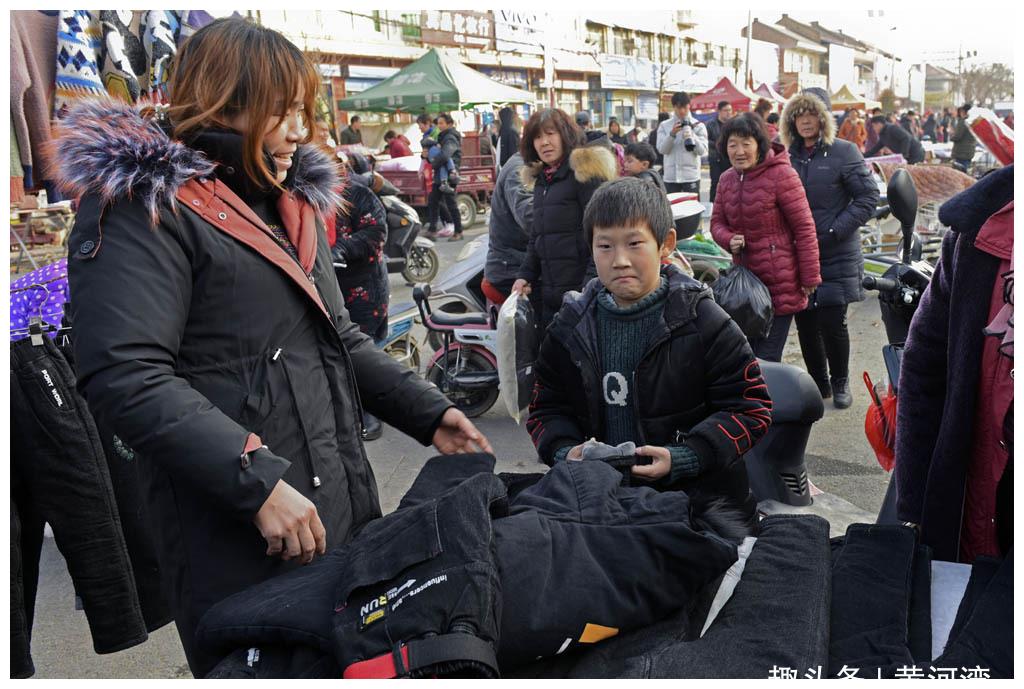 山西农村腊月集市年味浓浓,在外打工的父母回乡给孩子买新衣服