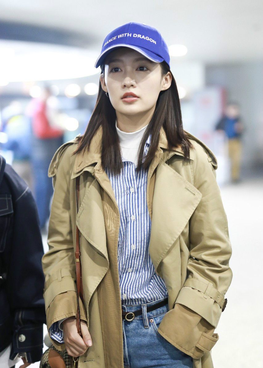李沁戴蓝色棒球帽穿风衣现身机场,面带微笑挥手打招呼尽显亲和