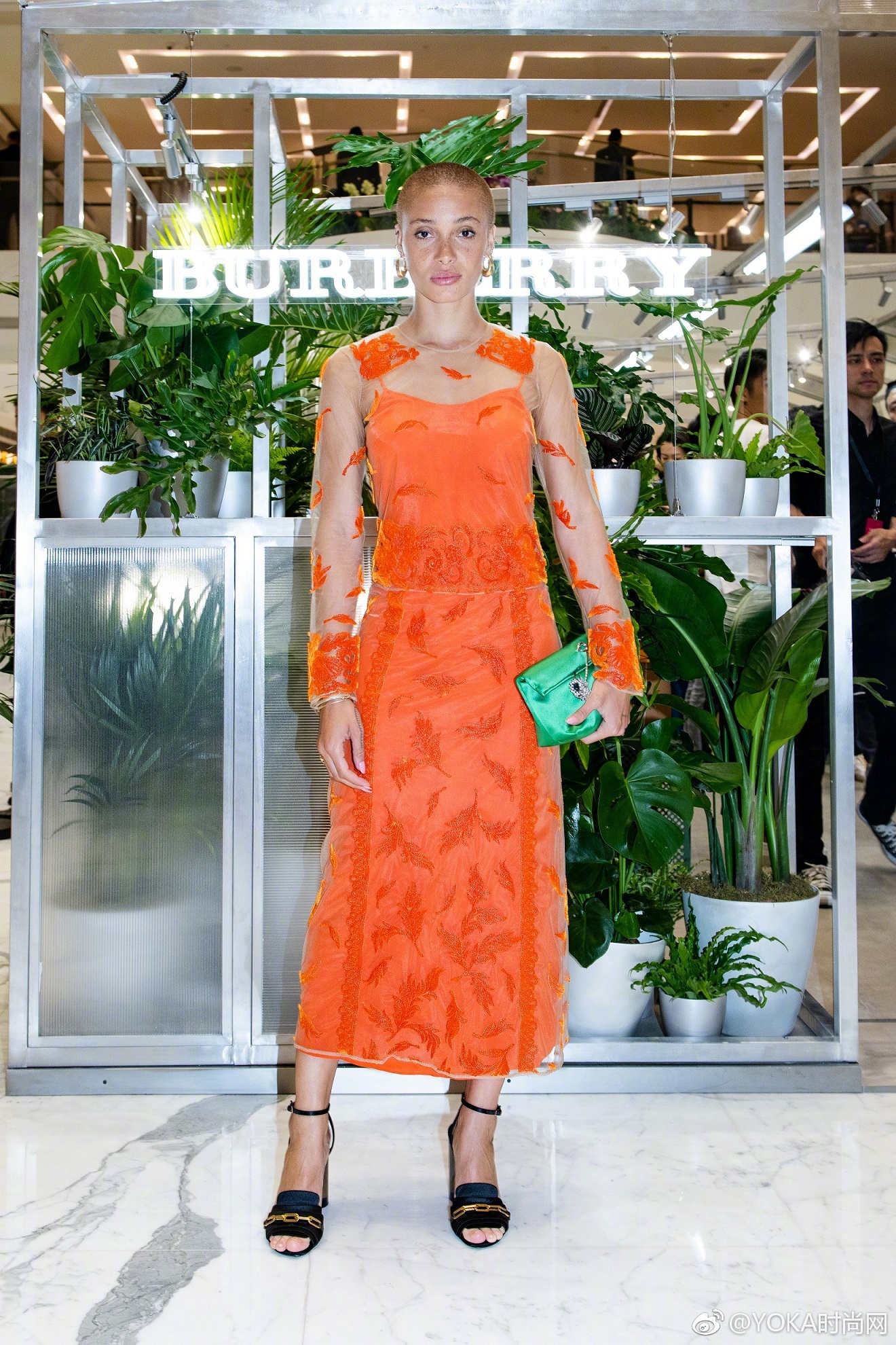 身穿一袭橙色透视连衣裙,脚踩一双黑色绑带高跟鞋,加上寸头和雀斑作为