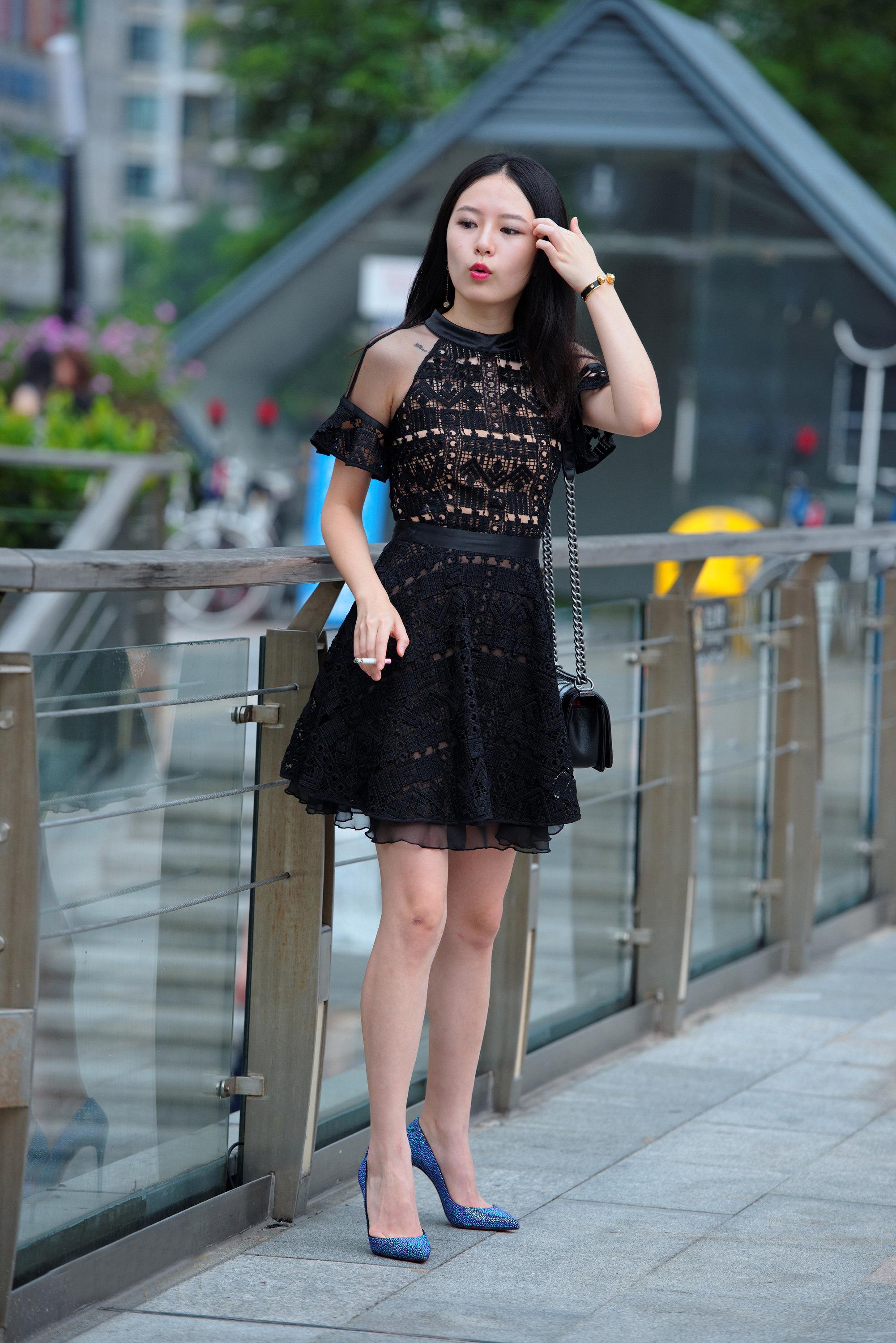 时尚街拍:黑色连衣裙美女性感撩发,手里的香烟分外抢眼