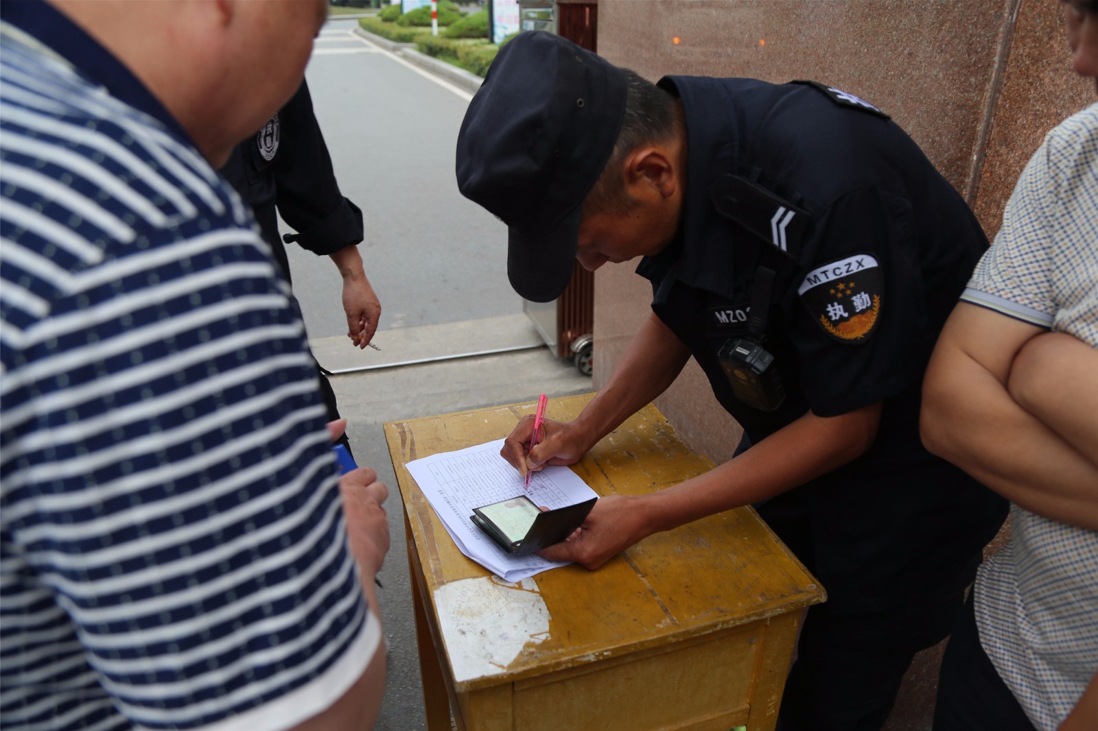 學校安保人員在認真核對送考大巴車司機證件,辦理進入校園相關手續