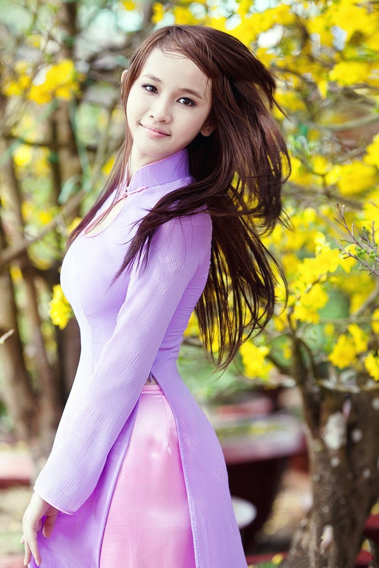 一个依偎在开满鲜花边的唯美长发微笑女孩